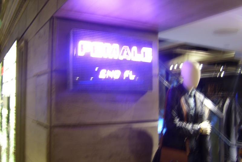 A neon pink sign in a department store that says "Female" and "2nd floor"